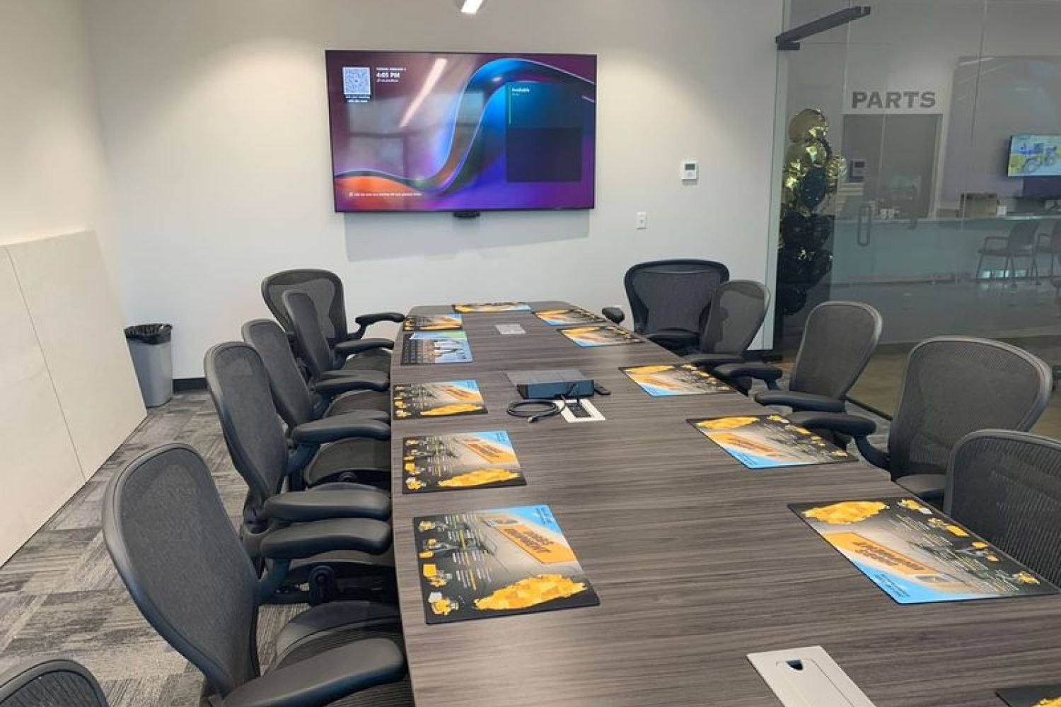Conference room with a long table, black chairs, and a wall-mounted display