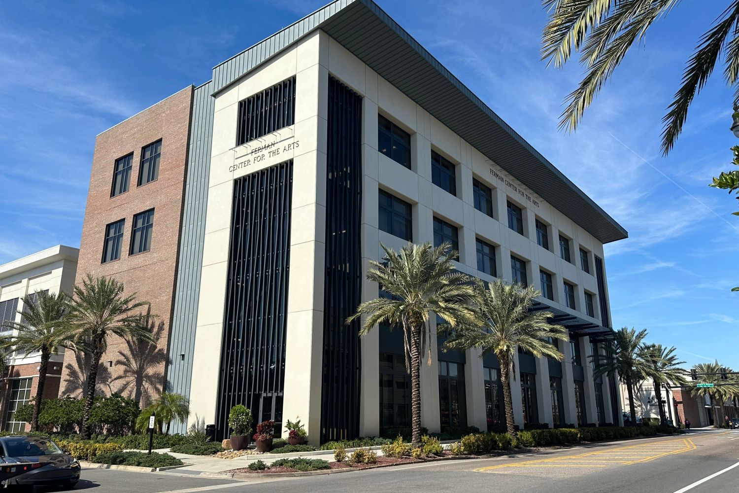 Ferman Center for the Arts building with palm trees and a blue sky