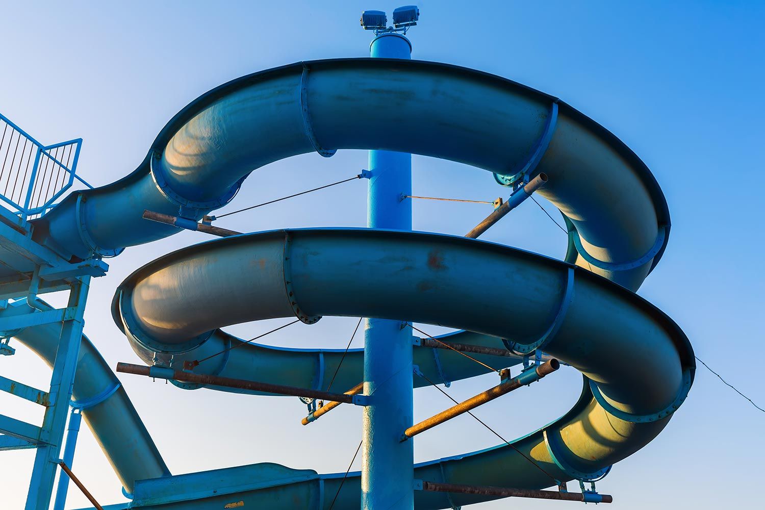 Large blue water slide with a spiral design under a clear sky